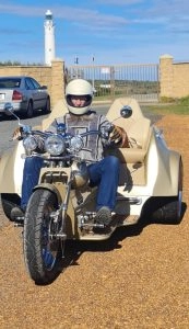 A man in a white helmet embarks on exciting trike tours, confidently navigating his motorcycle.